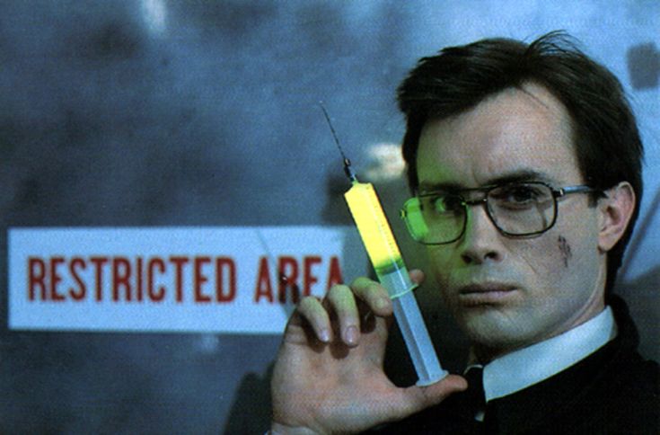 An screenshot of the movie Reanimator, as Herbert West glamour shots while holding a glowing syringe